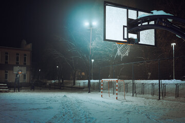 Night scene of basketball hoop during winter with snow