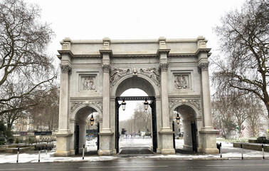 Fototapeta premium Marble Arch monument in London during a winter snowfall with city pedestrians.