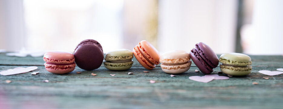 Colorful macarons arranged in a row on a old wooden table.