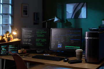 Dual monitors on wooden desk displaying programming code and cybersecurity data, desktop computer tower, keyboard, mouse, coffee cup, apple, and notepad in office setting