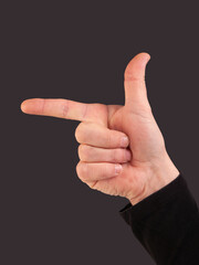 Man hand with fingers in gun gesture on a black background with copy space