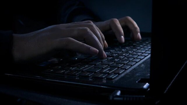 Night. Extreme close-up hands of unrecognizable hacker programmer working typing on keyboard laptop computer at dark room. Freelancer using laptop working from home, soft blue color.