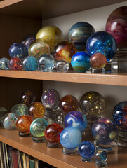 Shelf of colorful glass spheres each holding a unique galaxy with vivid celestial displays inside