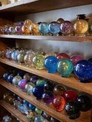 Shelf of colorful glass spheres each holding a unique galaxy with vivid celestial displays inside