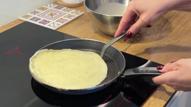Flipping a Thin Pancake in a Frying Pan on an Induction Stove