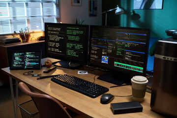 Empty workspace showing multiple computer monitors displaying programming code and system information, tablet with code, keyboard, mouse, coffee cup, apple, and electronic components on wooden desk