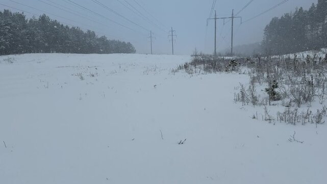 Panning Shot of a Snowy Field and Dashing Power Lines