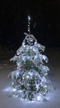 Decorated Christmas Tree Outdoors During a Night Snowstorm