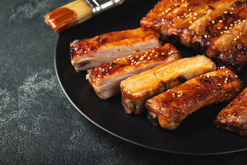Hot grilled spare ribs from a summer BBQ served on a plate with sauce. Top view. Copy space