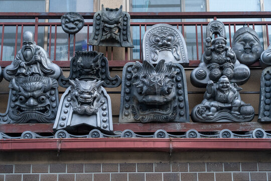 View of a collection of ornate, weathered rooftop ornaments featuring various deity and demon faces line a building's edge, Kyoto, Kyoto, Japan.