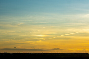 Fototapeta premium Scenic Sunset Over Forest Silhouette with Contrails in the Evening Sky