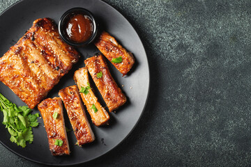 Hot grilled spare ribs from a summer BBQ served on a plate with sauce. Top view. Copy space