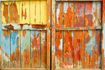 Old wooden door with ruined multicolored decoration
