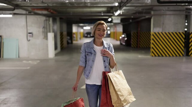A woman loads shopping bags into the trunk of her car in an underground parking garage