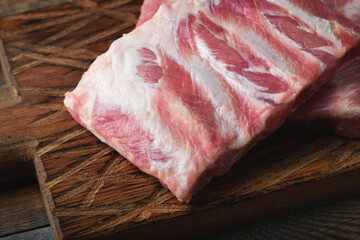 Raw pork ribs with spices, salt and rosemary on dark wooden background