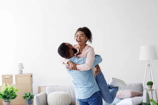 Happy couple moving at bought house, husband lifts up beloved wife, family begin new life at first dwelling, copy space. Loan and mortgage, bank lending, relocation at own apartment, rent flat