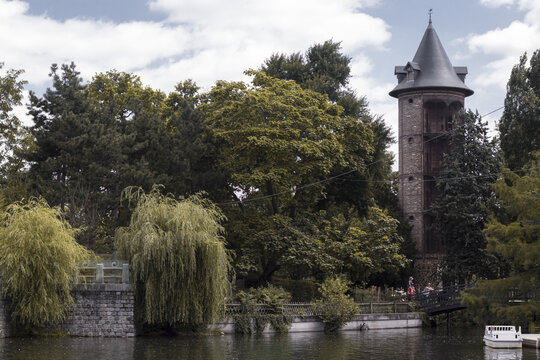 View of a stone tower rises above the lush greenery, its conical roof silhouetted against the sky, reflected in the serene waters, Paris, &Atilde;Žle-de-France, France.
