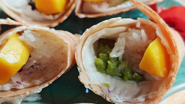 Sticky rice wrapped with mango filling and young coconut cream, served on a plate.