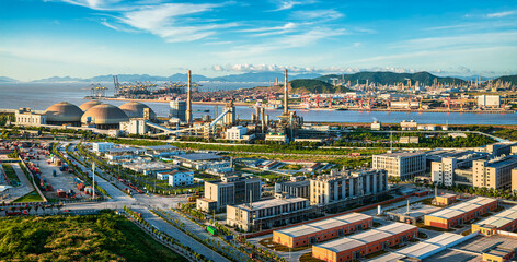 Vibrant industrial port and factory complex located along the coast under a clear blue sky during the day.