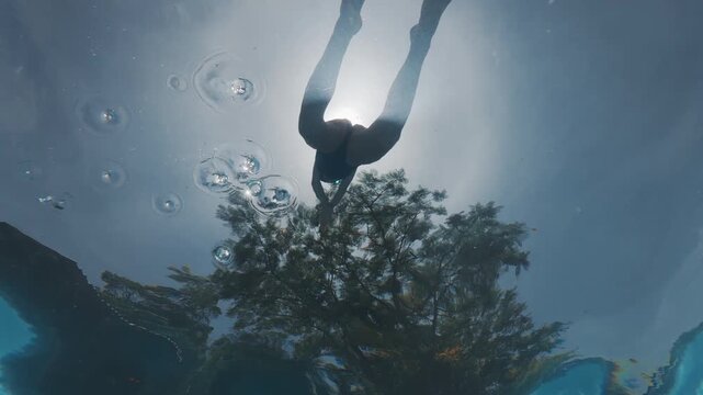 Girl swims underwater in the pool. Pre teen girl feels herself comfortable and relaxed underwater. Little girl dives and swims in the pool