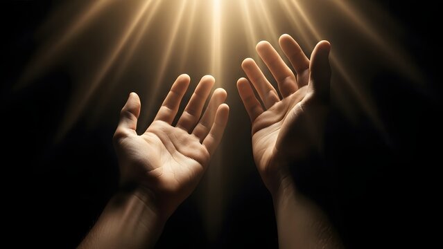 Human hands reaching up toward divine glowing light beams. Hope and spirituality concept. Person stretching arms toward heaven in dark background with bright celestial rays