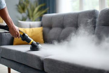 Sofa chemical cleaning with professionally extraction method. Upholstered furniture. Early spring cleaning or regular clean up. Dry cleaner's in light red protective glove employee removing dirt from