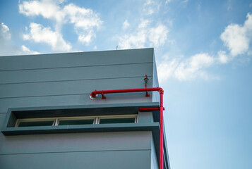 Height limit warning structure with industrial piping system under a clear sky.Red fire protection pipes and steel structure installed on a modern warehouse exterior.