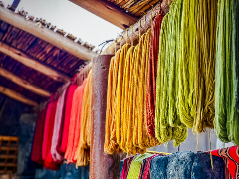 Aerial view of brightly colored skeins of yarn hanging in vibrant rows, their rich hues a feast for the eyes, Cusco, Peru.