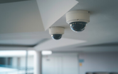 Obraz premium Ceiling mounted CCTV security camera in a modern indoor hallway for surveillance and continuous monitoring for safety crime prevention smart building technology and professional security systems.