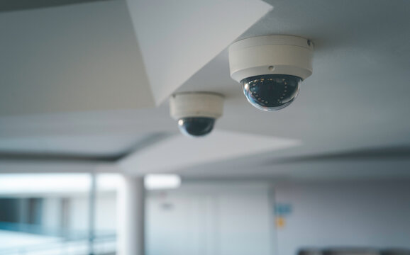 Ceiling mounted CCTV security camera in a modern indoor hallway for surveillance and continuous monitoring for safety crime prevention smart building technology and professional security systems.