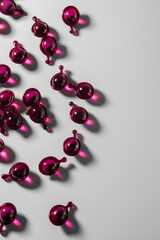 Scattered deep pink serum capsules with a tail on a light gray background