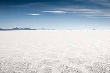 Salar de Uyuni salt flat in Bolivia. White salt crystal surface and and the blue sky with clouds.