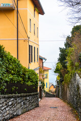 Old colorful architecture on cobblestone street in Brunate village, Como lake, Italy.