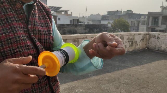 Jaipur, India 12 January 2026: Picture of hands of a person holding a kite string reel preparing for kite flying
