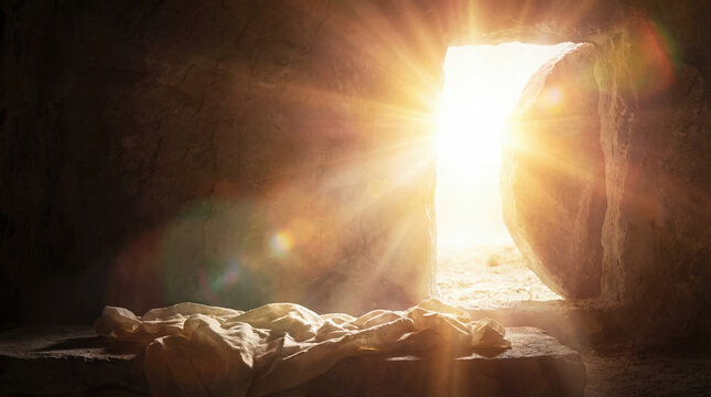 Empty tomb of Jesus with rolled stone and burial linens on slab. Bright divine light streaming into dark cave. Biblical concept of Resurrection miracle and Easter Sunday victory.