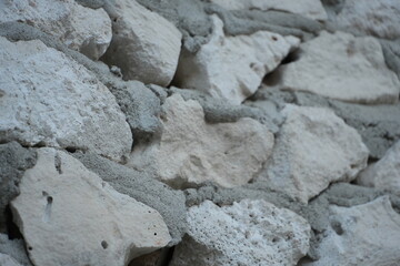 Fototapeta premium Irregularly shaped white and gray stones are cemented together to form a textured wall.