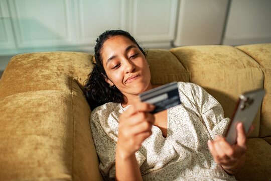 Young adult woman looking thoughtful while shopping online at home
