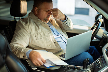 Adult man stressed working on laptop in parked car