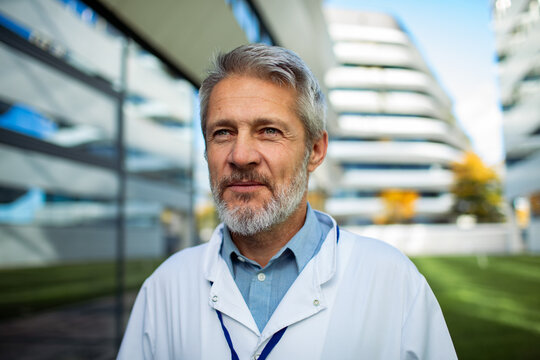 Mature male doctor looking confident outside modern hospital