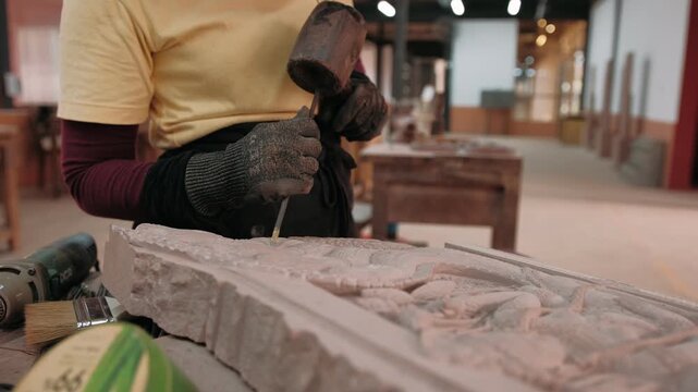 Close up of hands carve an stone bas relief design using a chisel and hammer to meticulously, Siem Reap, Cambodia.