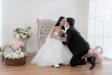 Romantic groom proposing to bride with bouquet in elegant wedding photoshoot