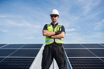Technician installing solar panels on factory roof for green energy. A skilled technician in safety gear is working on a solar panel installation on rooftop.