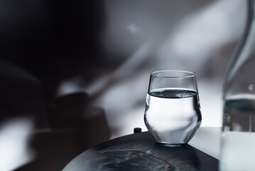 a glass of drinking water on white table in  morning sunlight.