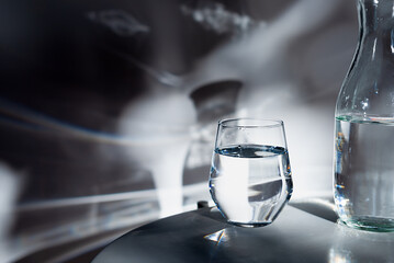 a glass of drinking water on white table in  morning sunlight.
