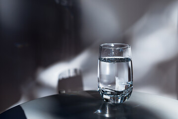 a glass of drinking water on white table in  morning sunlight.