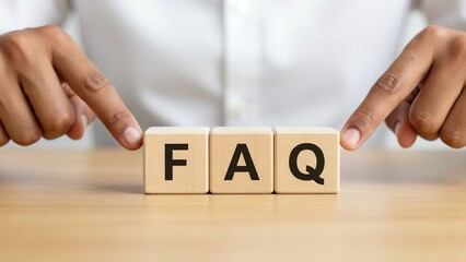 Naklejka premium Hands pointing at wooden blocks spelling FAQ on a wooden table, representing frequently asked questions and information.