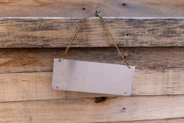 Blank sign hanging on a wooden wall in a quiet area near a building during daytime