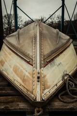 Rustic boat rests on weathered dock, embracing the tranquility of a cloudy afternoon by the water