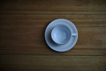 Top view of a empty white cup on a wooden table.