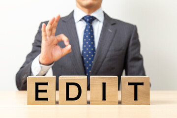 「EDIT」と書かれたブロックとOKポーズをするビジネスマン